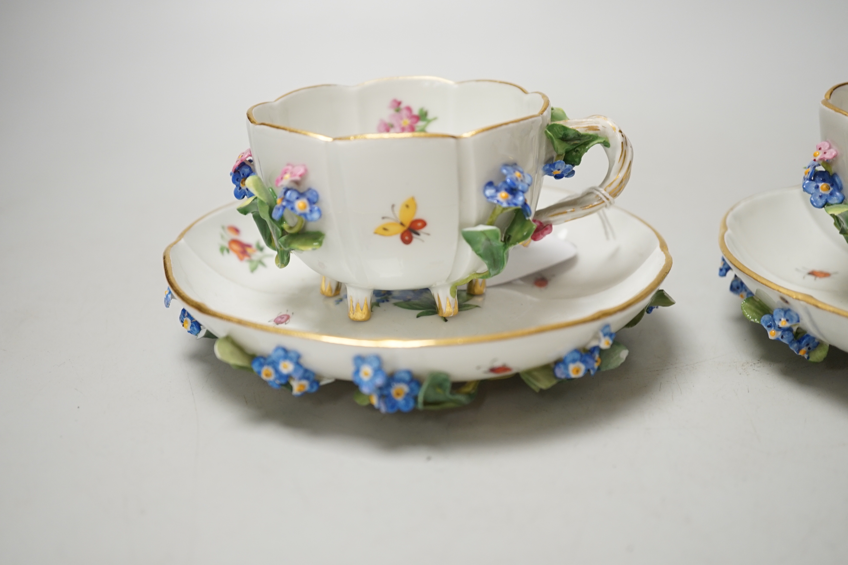 A pair of Meissen floral-encrusted cabinet cups and saucers, late 19th century, saucers 14cm diam.